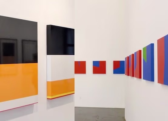 PSJM exhibition at Casa de América featuring geometric artworks in various colors. 