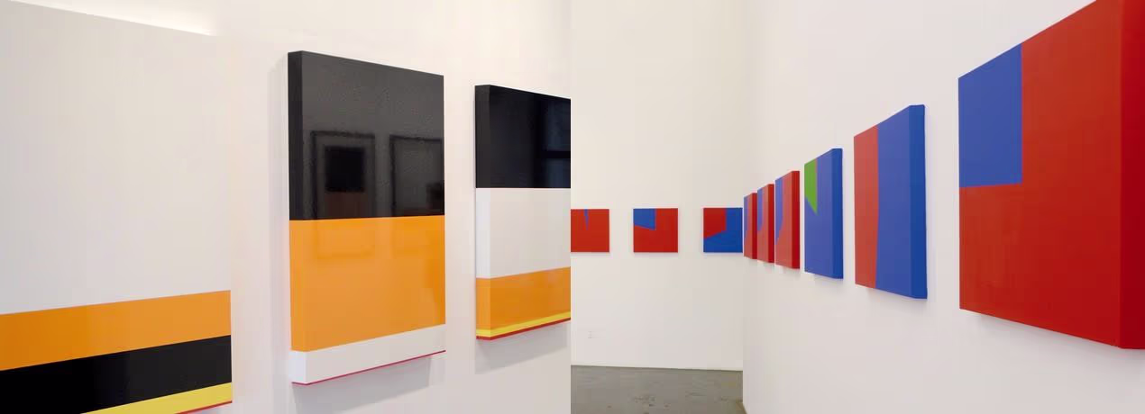 PSJM exhibition at Casa de América featuring geometric artworks in various colors.