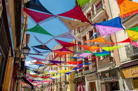 Colorful street decorations over a Madrid street with traditional balconies and buildings