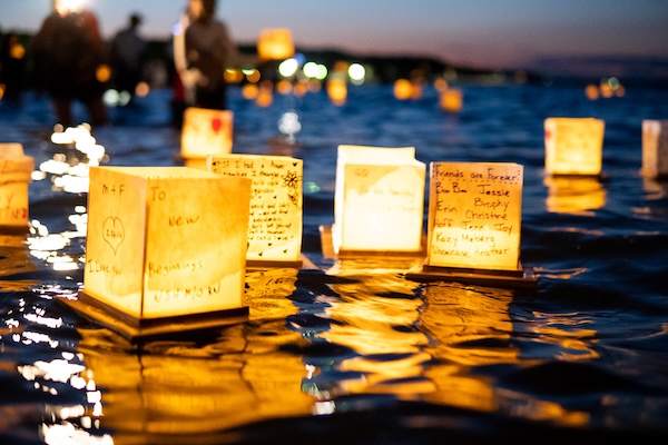 Floating candle lanterns with handwritten messages glowing on water at night