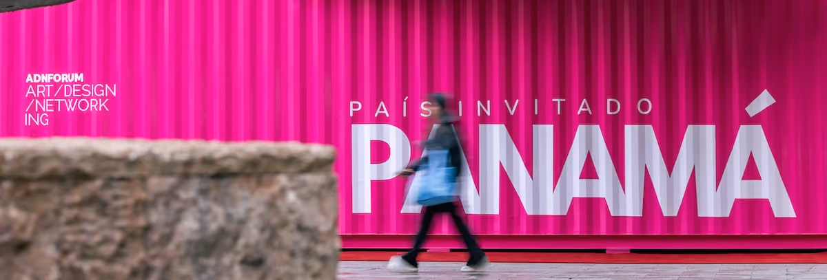 Un peatón camina junto a un vibrante contenedor rosa del ADN Forum en Madrid