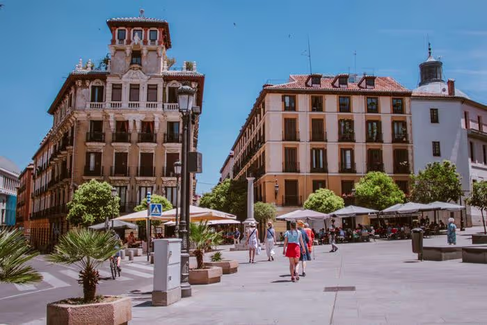 A vibrant street scene in Madrid featuring classical architecture and bustling activity in the square.