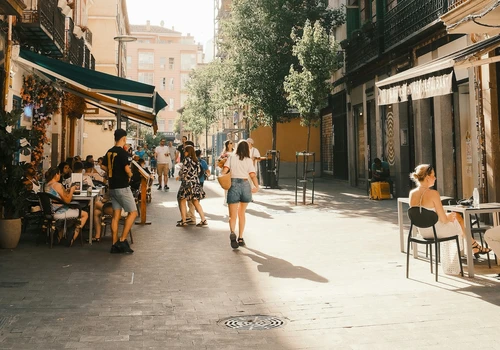 People walking past cafe terraces on a sunlit Madrid street