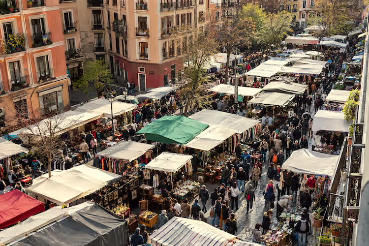 Aerial view of El Rastro flea market in Madrid, with rows of stalls and crowds browsing the market.