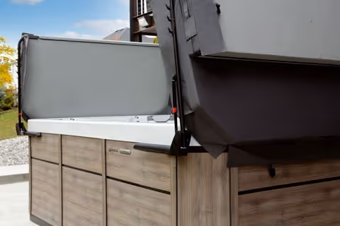 A set of cover lifters in action, holding a spa cover open with mechanical arms.