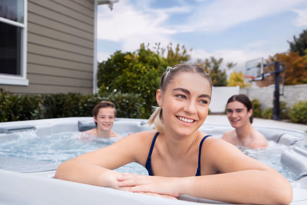 A woman happily looking out from her seat in a spa, with her family sitting in adjacent spa seats behind her.