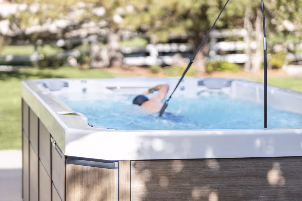 A person swimming in a Swim Series spa on a patio.