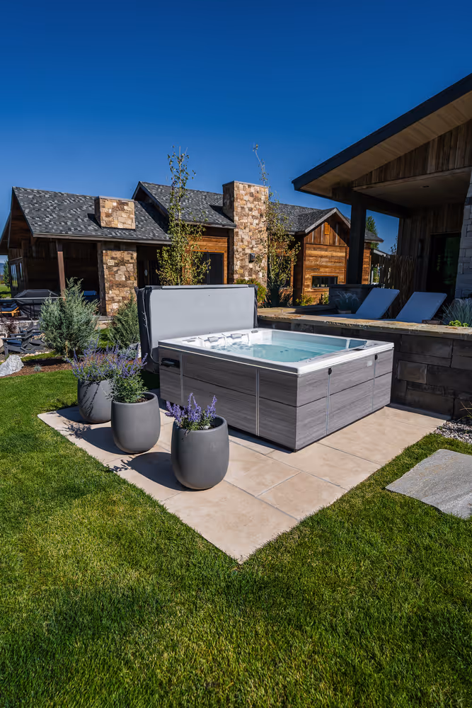 An M6 spa on a dedicated patio next to planters.