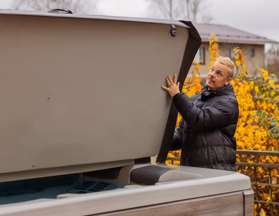 A man lifting the cover off his A7D spa to prepare for use.