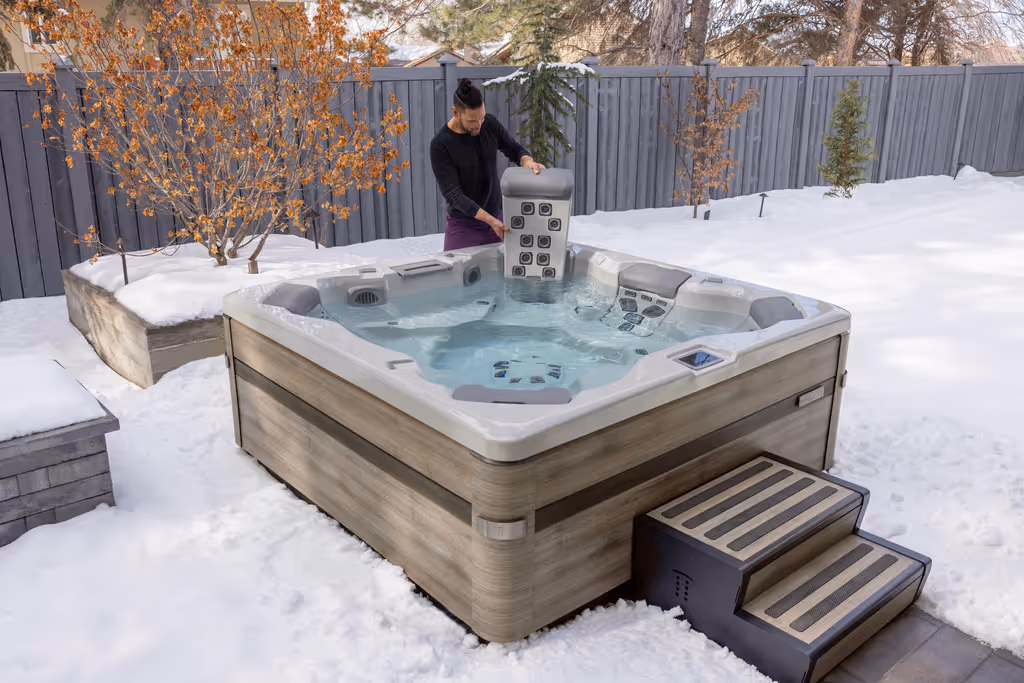 A man holds a JetPak massager next to his A series spa.