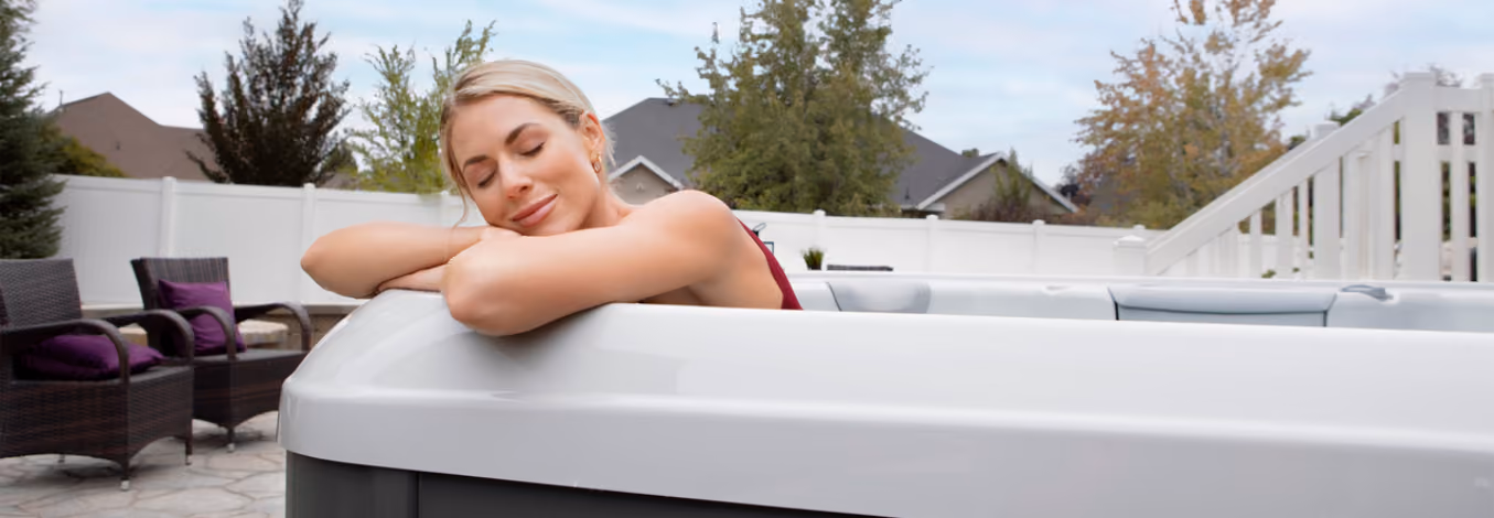 A woman relaxing and resting on the edge of a X series spa.