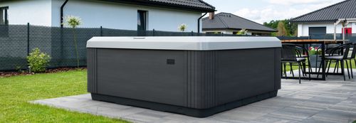 A calm series spa in a backyard, in front of a neighboring home.