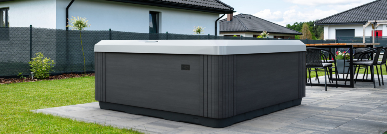 A calm series spa in a backyard, in front of a neighboring home.