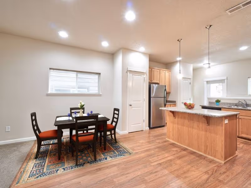 Dining area with table and chairs with view of kitchen with breakfast bar
