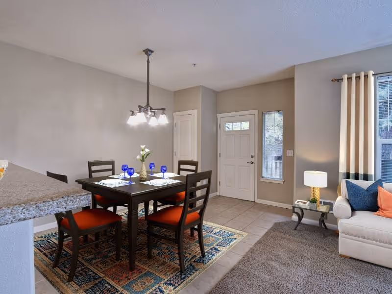 Virtually staged living area with tv featuring view of dining area with table chairs and kitchen
