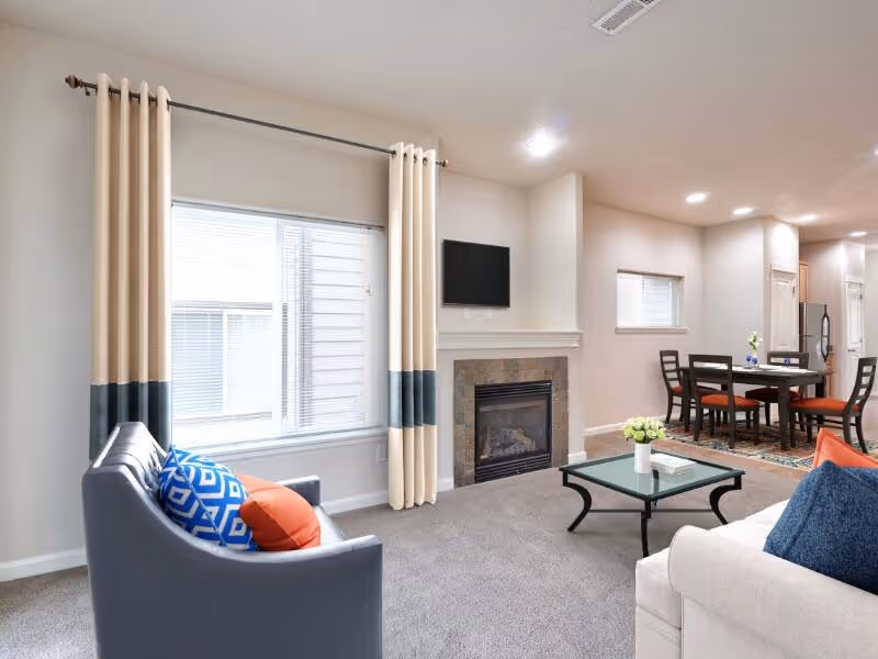 Virtually staged living area with sofa, coffee table, fireplace, and large window