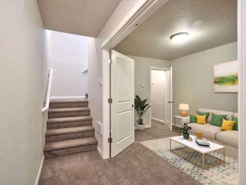 Virtually staged seating area with sofa with view of stairs to second floor 