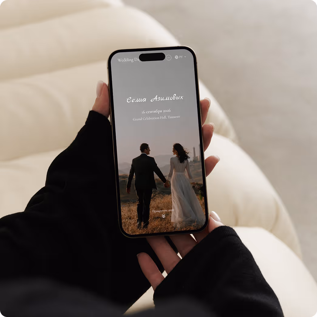 Руки в черных рукавах держат смартфон с экраном свадебного приглашения Азимовых на 16 сентября 2026 года с изображением пары в свадебной одежде на природе.