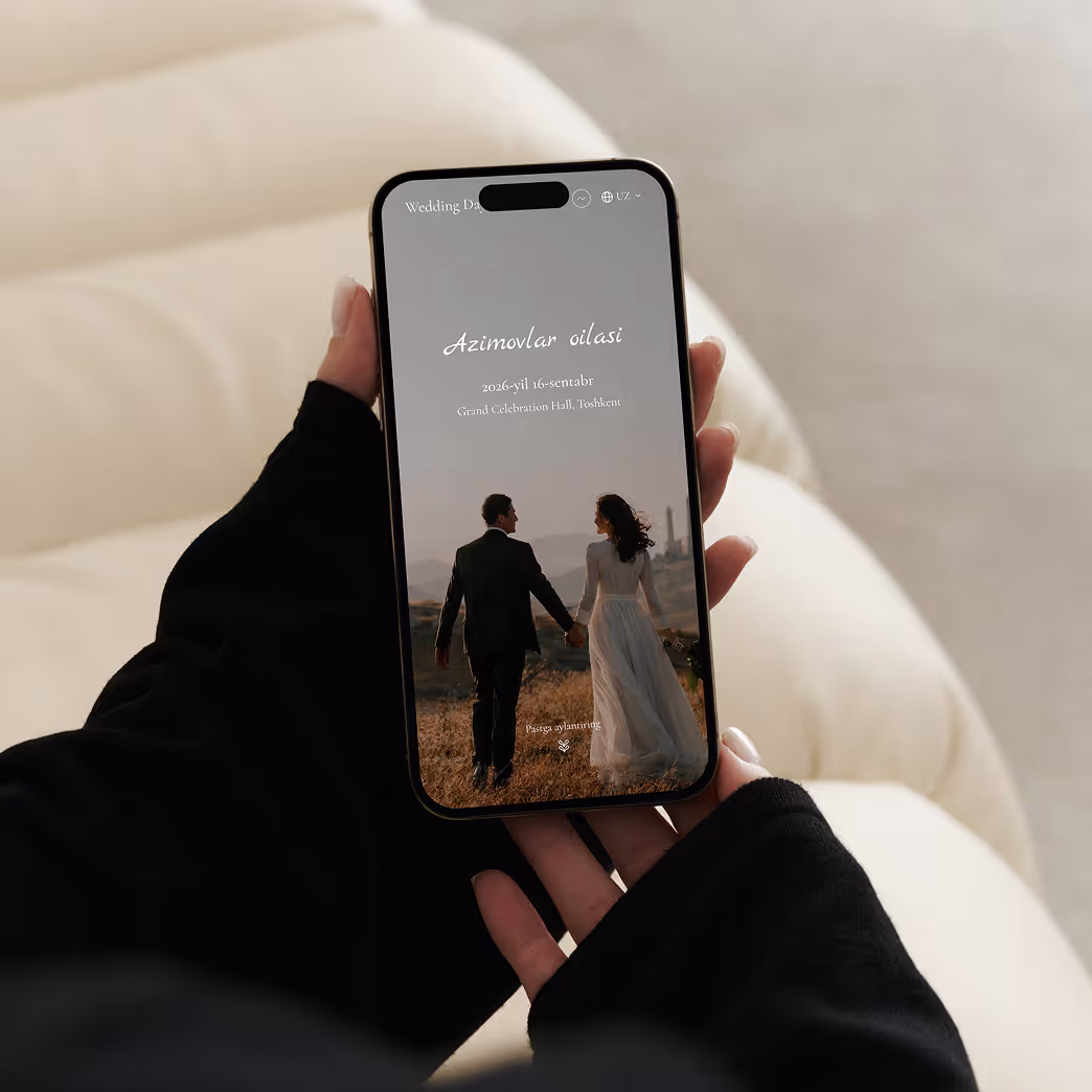 Руки в черных рукавах держат смартфон с экраном свадебного приглашения Азимовых на 16 сентября 2026 года с изображением пары в свадебной одежде на природе.