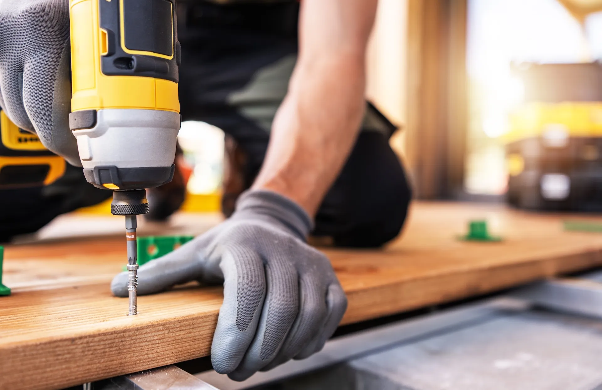 A skilled worker uses a power-drill on wooden plank
