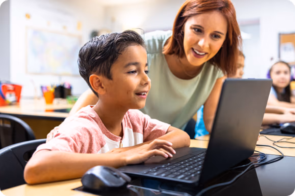 Boy playing Dodgy or Not? on a laptop with a teacher's assistance