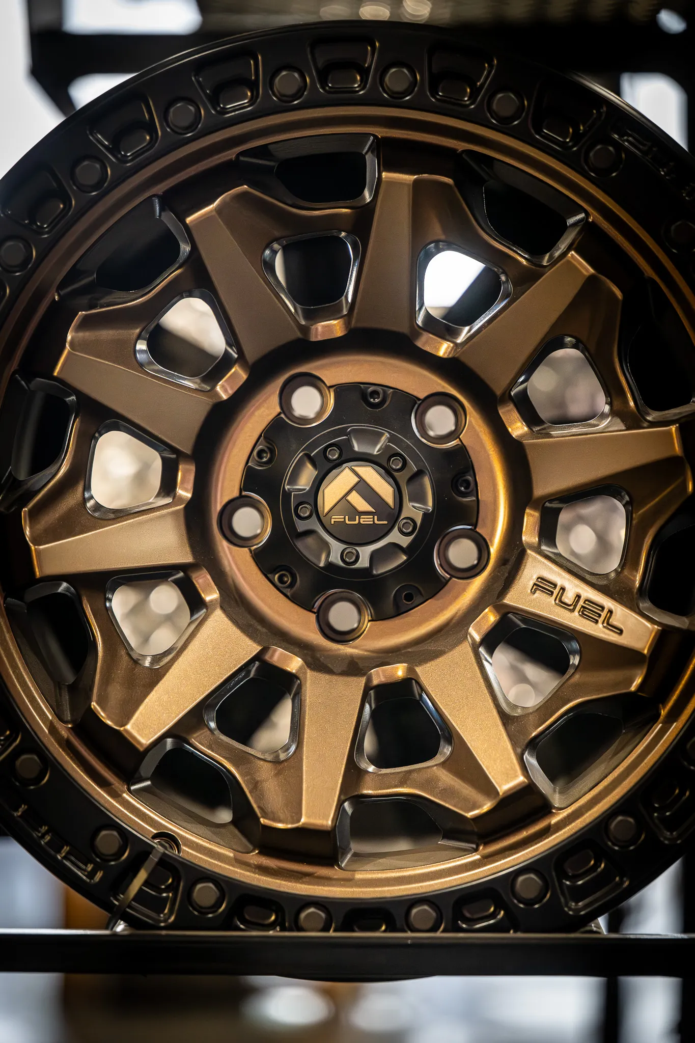 Close-up of a fuel off-road wheel in matte bronze finish with a black beadlock-style ring and fuel logo center cap on a display rack