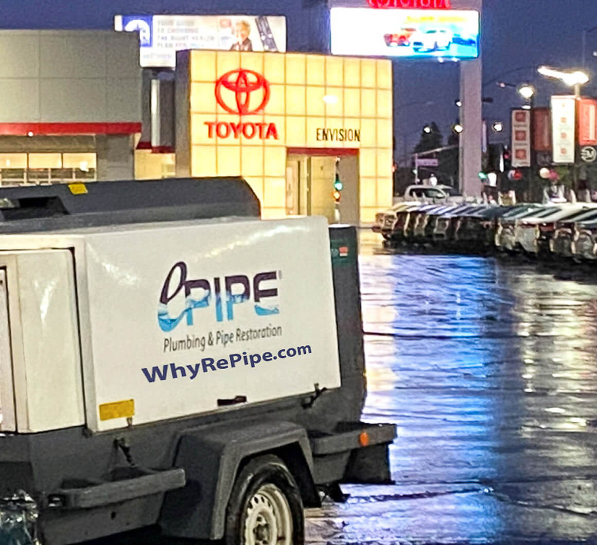 White RePipe plumbing and pipe restoration trailer parked outside a Toyota dealership at night.