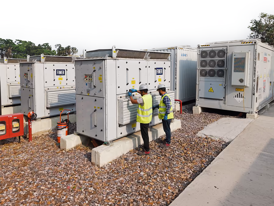 Workers in hi-vis vests inspect battery cabinets at the Kilokari battery energy storage site in New Delhi, India