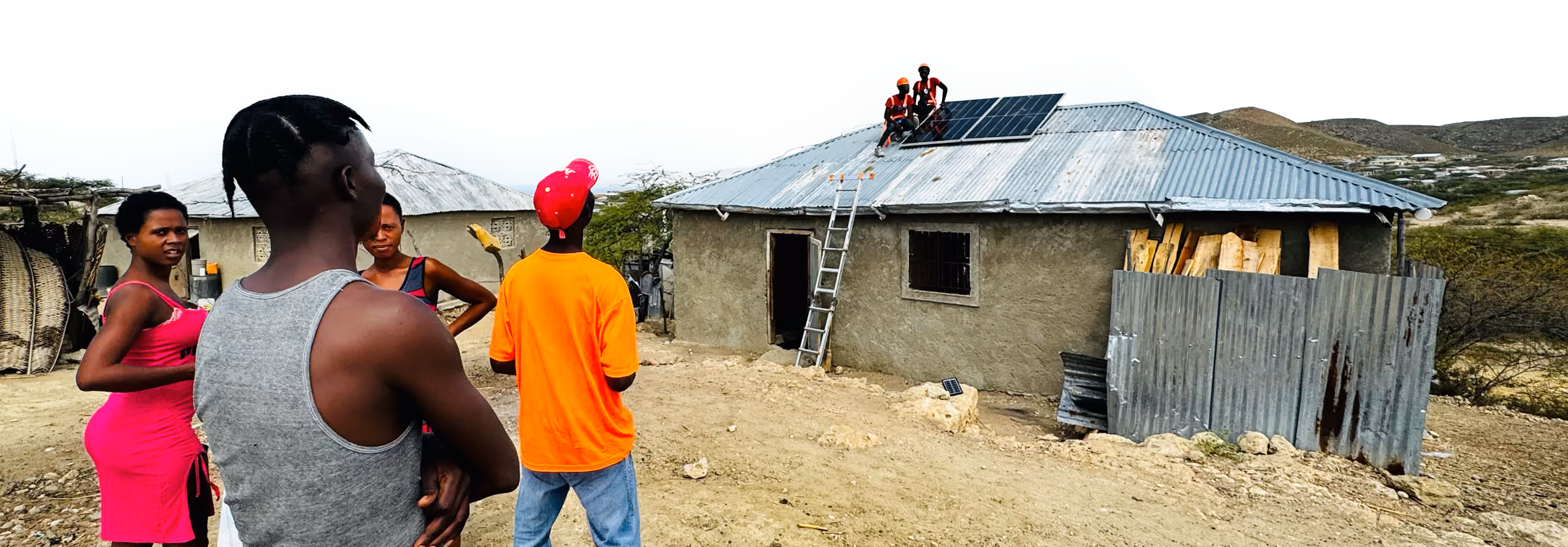 Residents watch as installers fit solar panels to the roof of a house in rural Haiti