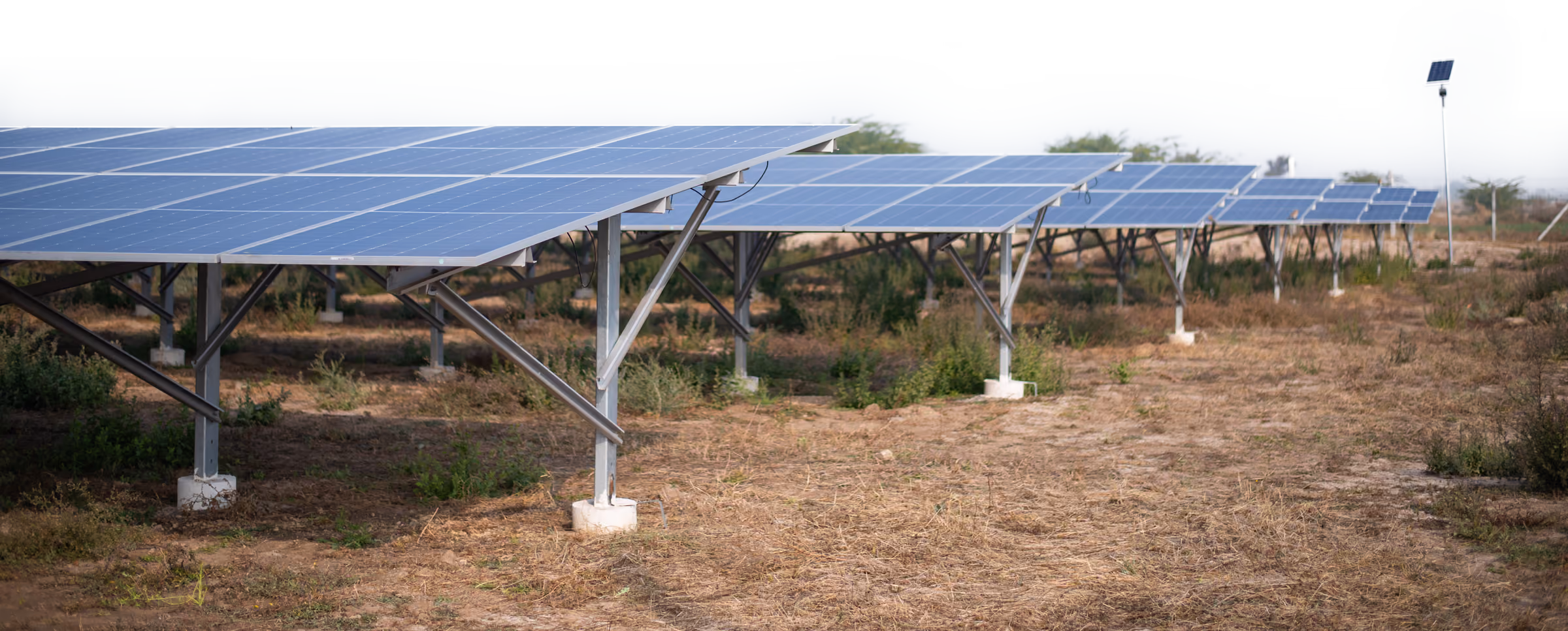 Rows of ground-mounted solar panels on dry farmland in Rajasthan, India