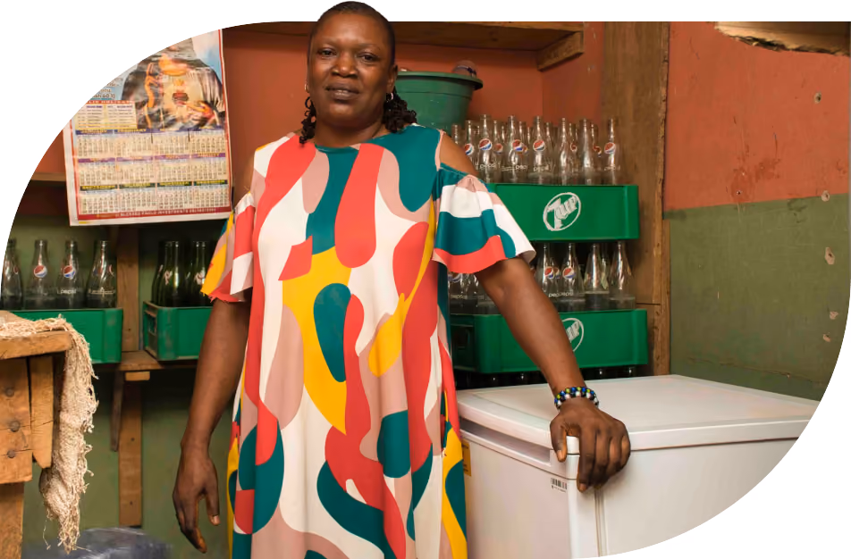 Helen Obina stands beside the solar-powered refrigerator in her shop in Nigeria