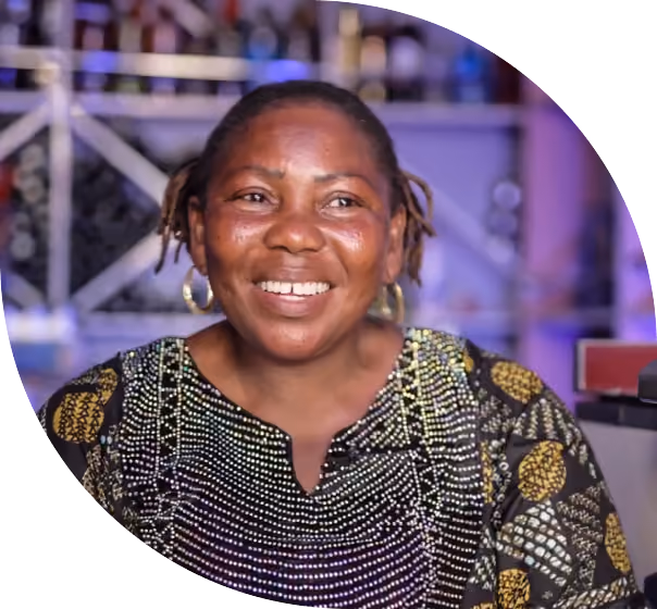 Doris Chuwa smiles behind the counter of her bar in Nigeria, where a solar-powered chiller keeps drinks cold
