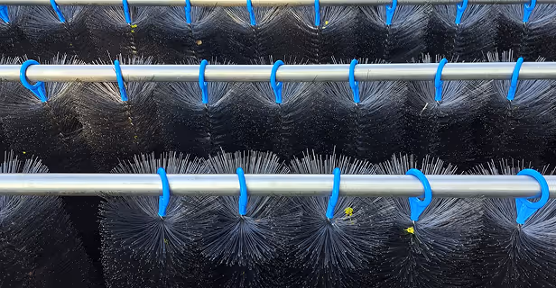 Mehrere große runde Bürsten mit schwarzen Borsten an Metallstangen befestigt, vermutlich industrielle Reinigungsbürsten.