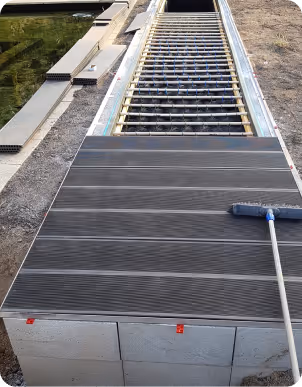 Teilweise verlegtes Terrassendielen-Bodenbelag mit einem Besen auf der rechten Seite.