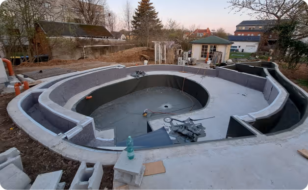 Unterirdischer Schwimmbeckenbau in einem Garten mit unvollständiger Konstruktion aus Beton und Ziegeln.