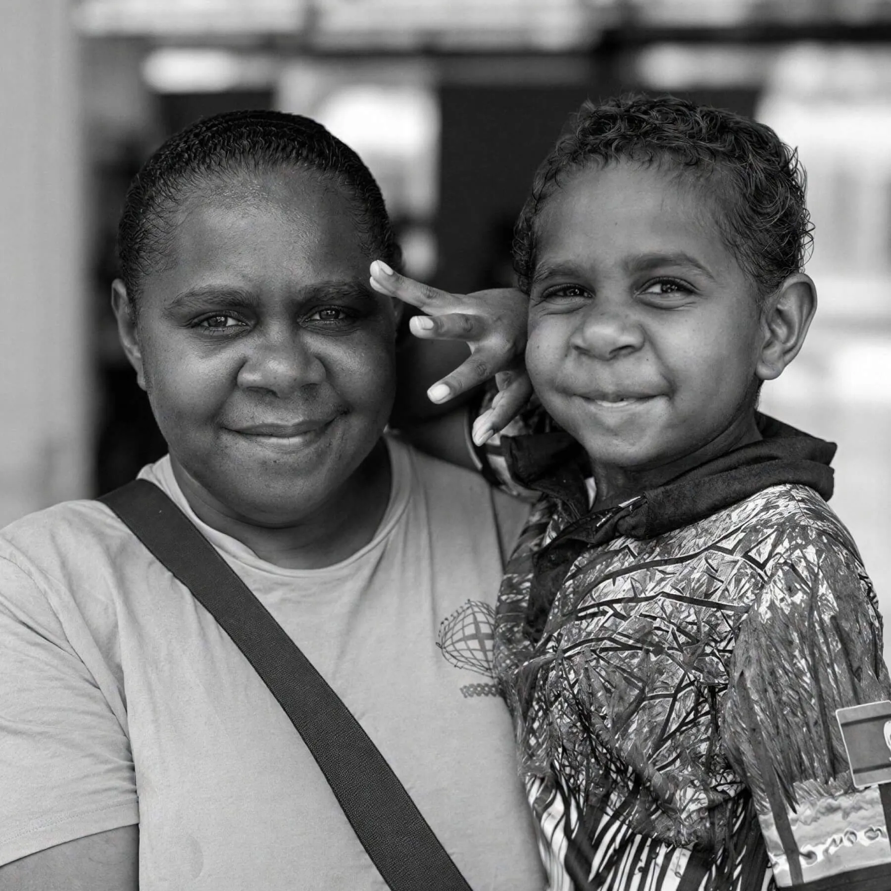 First Nations Elder embracing a young girl, both smiling, black-and-white photograph
