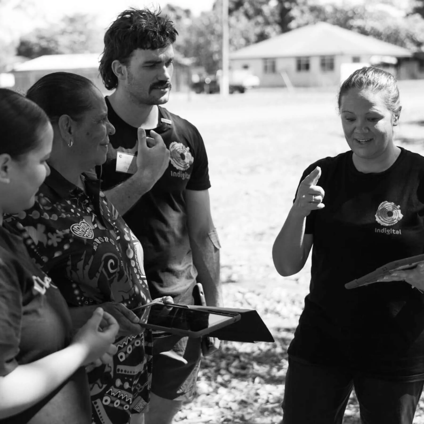 Indigital team members working alongside community members on a shared project, black-and-white photograph