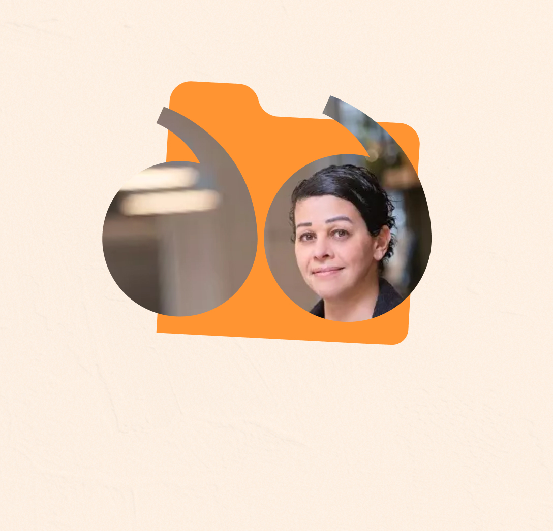 Portrait of a woman with dark hair styled back, smiling slightly, framed within yellow quotation marks on a pale background.