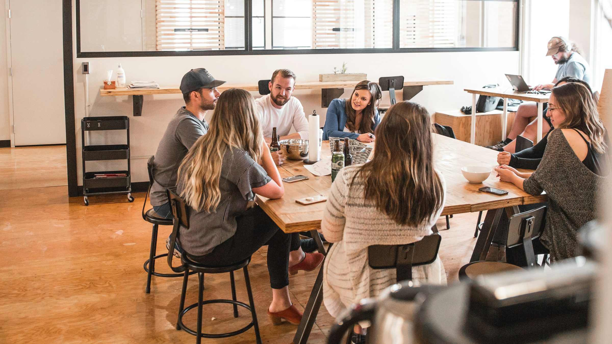 A team talking around a shared wooden table in an open-plan office
