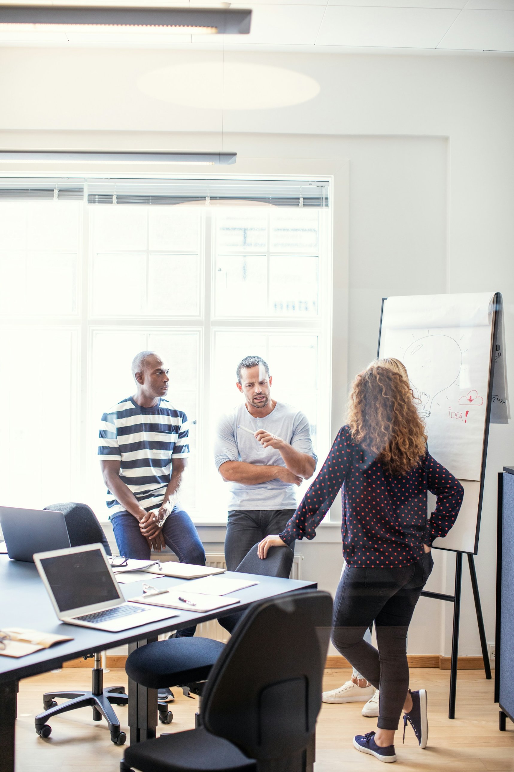 Colleagues discussing ideas around a flipchart in a bright meeting room