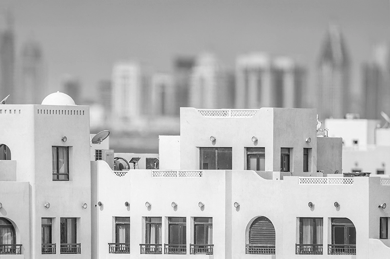 White modern buildings with rectangular windows and balconies, city skyline blurred in the background. MINA Port, Doha, Qatar.