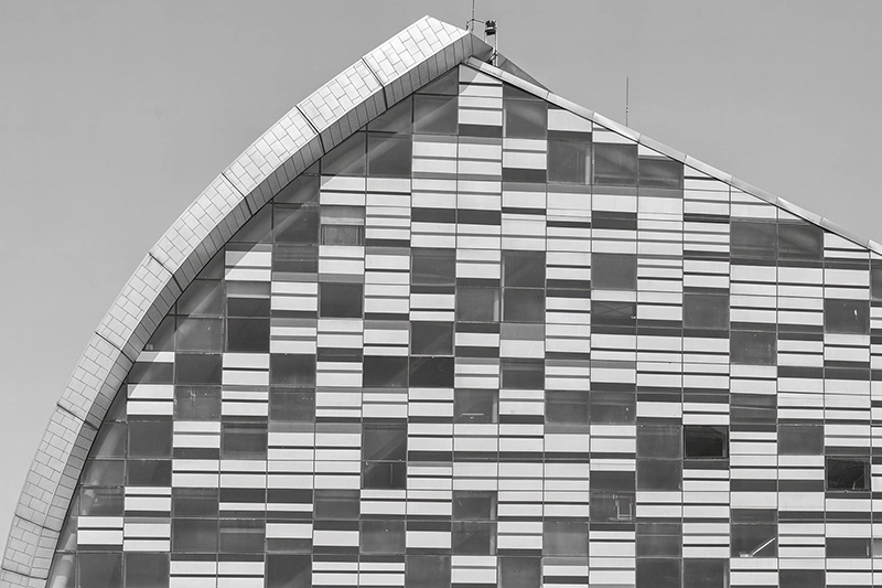 Facade of a modern building with curved edge and rectangular glass panels arranged in a striped pattern. Sidra Hospital, Al-Rayyan, Qatar.