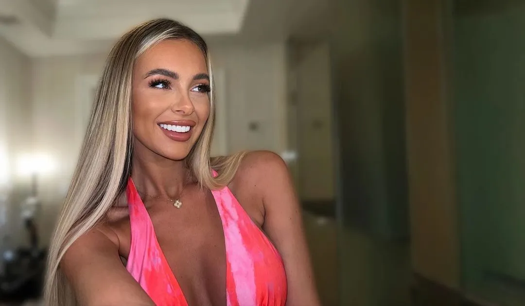 A woman in a pink dress posing for a picture.