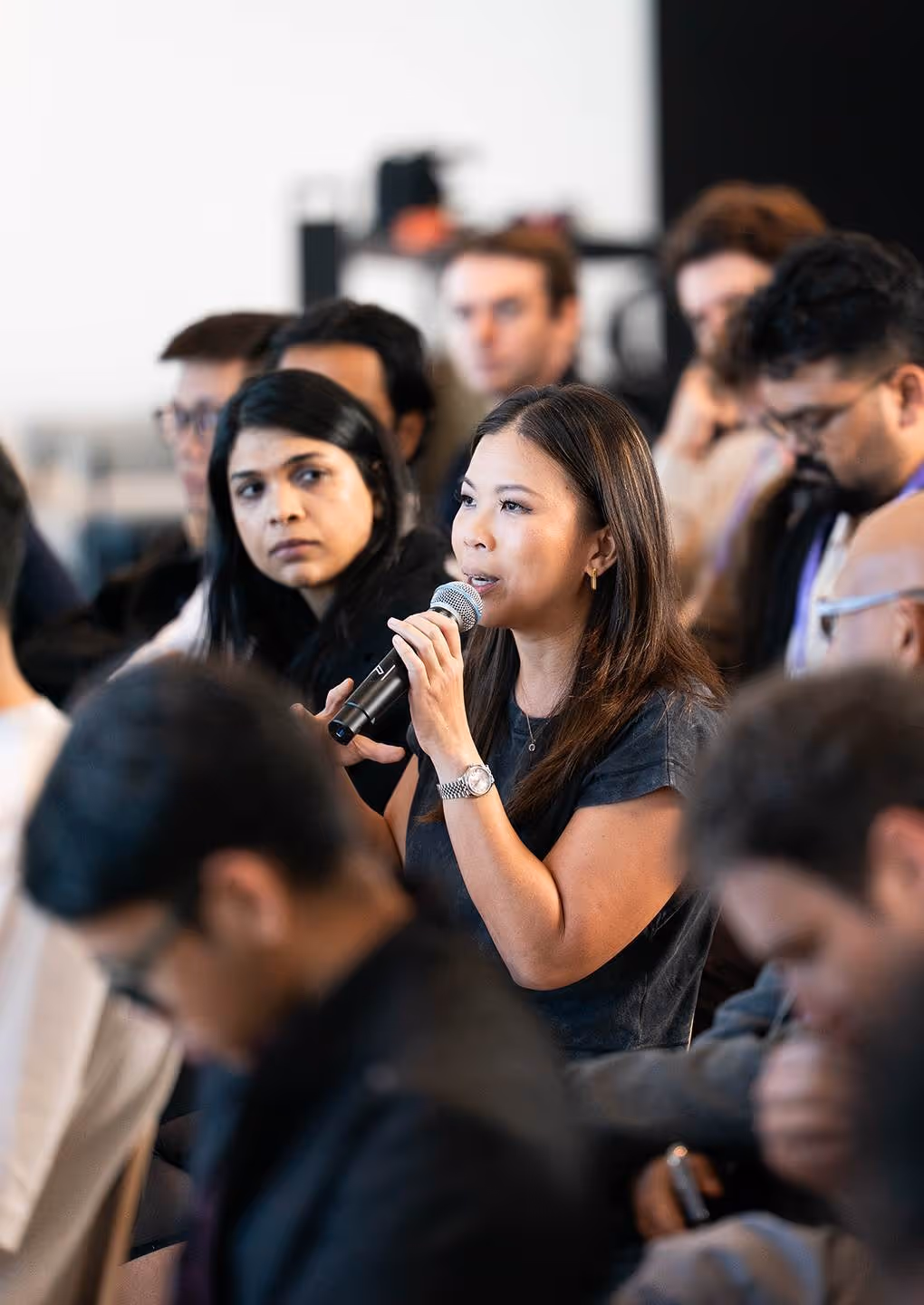 Woman speaking into microphone during a group meeting or conference discussion.