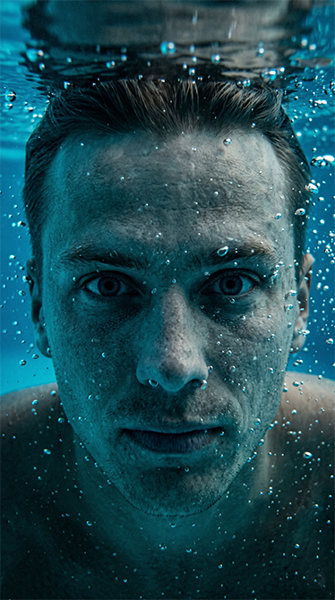 Group of business professionals engaging and networking at a conference with a table of appetizers in the foreground and digital data charts on screens in the background.