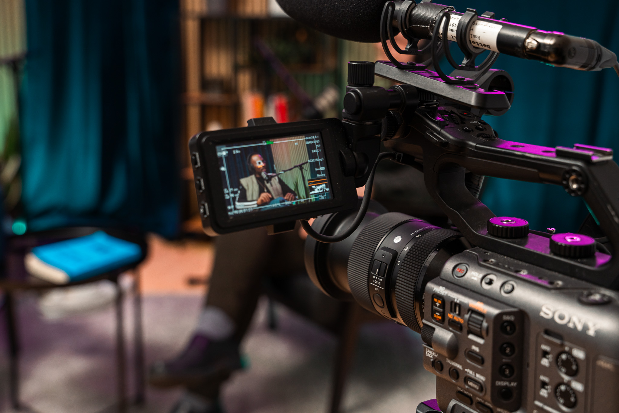 Professional Sony video camera recording a person speaking into a microphone in an indoor setting.