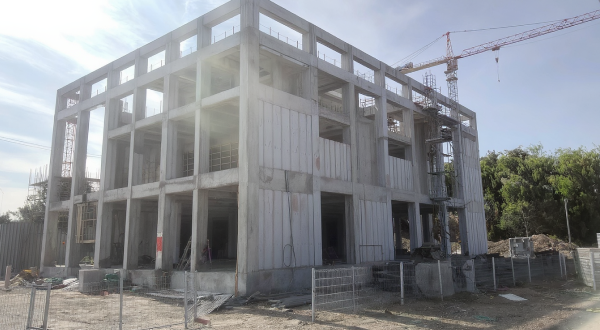 Ein Wohngebäude im Bau mit einem Baukran im Hintergrund.