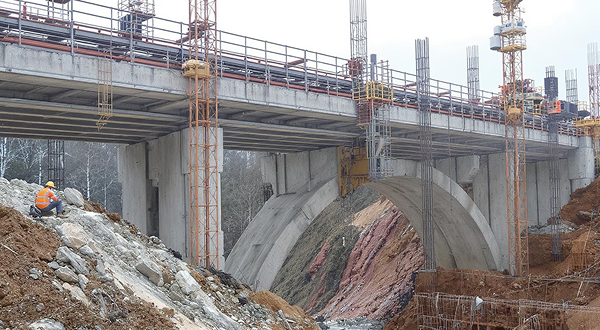 Eine Brücke im Bau mit mehreren Kränen und Stahlträgern.