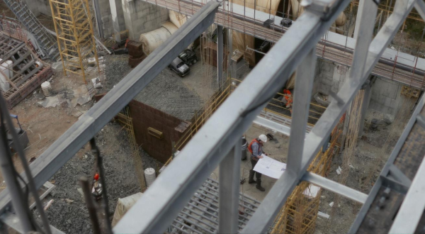 Blick auf eine Baustelle mit Stahlträgern und einem Bauarbeiter aus der Vogelperspektive.