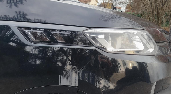 Seitenansicht von einem schwarzen Fahrzeug mit sichtbaren Scheinwerfern.
